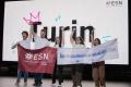 People cheering on a scenario in front of a big screen that says "Turin"